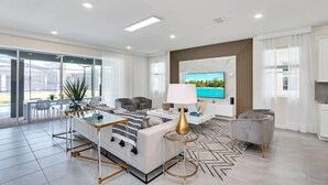 Een moderne woonkamer met een bank, salontafel, televisie en een eetgedeelte met stoelen en een tafel.