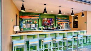 A bar area with a counter, multiple hanging pendant lights, and a row of bar stools. - Mickey | Pool | Surf Simulator | 7 Miles Disney 1600 (Kissimmee)