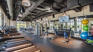 Un gimnasio con cintas de correr, máquinas de pesas y pelotas de ejercicio.