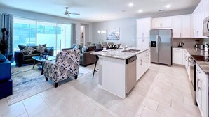 Una cocina moderna con una isla central, armarios blancos y electrodomésticos de acero inoxidable.