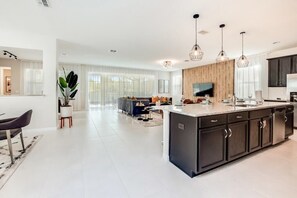 A modern kitchen with a central island, dark cabinetry, and pendant lighting.