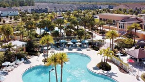 A resort with a large, curved swimming pool surrounded by palm trees and lounge chairs.