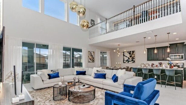 A spacious living area with a white sectional sofa, a blue armchair, and a coffee table. - Harry Potter | Harley Game Loft | Near Disney 1787 (Kissimmee)