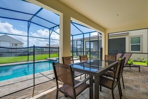 Relax on the patio with a clear view of the pool, surrounded by a well-maintained lawn and a setting.