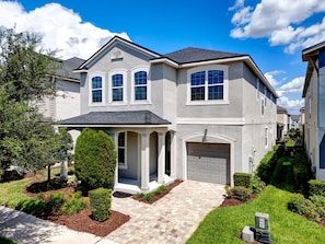 A two-story residential house with a garage, a covered porch, and a well-maintained front yard.