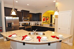 Enjoy cooking in this well-equipped kitchen with a granite countertop island, sink, and stainless steel appliances.