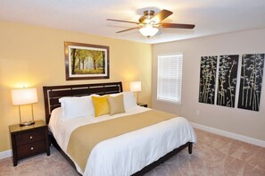 A bedroom with a bed, nightstands, a ceiling fan, a window with blinds, and wall art. - No Rear Neighbors | Resort | Pool | Game Room 4183 (Davenport)