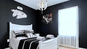 A bedroom with a white bed, black and white bedding, Star Wars-themed wall art, and a large window with curtains. - Waterpark | Private Pool | 6 Mi 2 Disney 4686 (Davenport)
