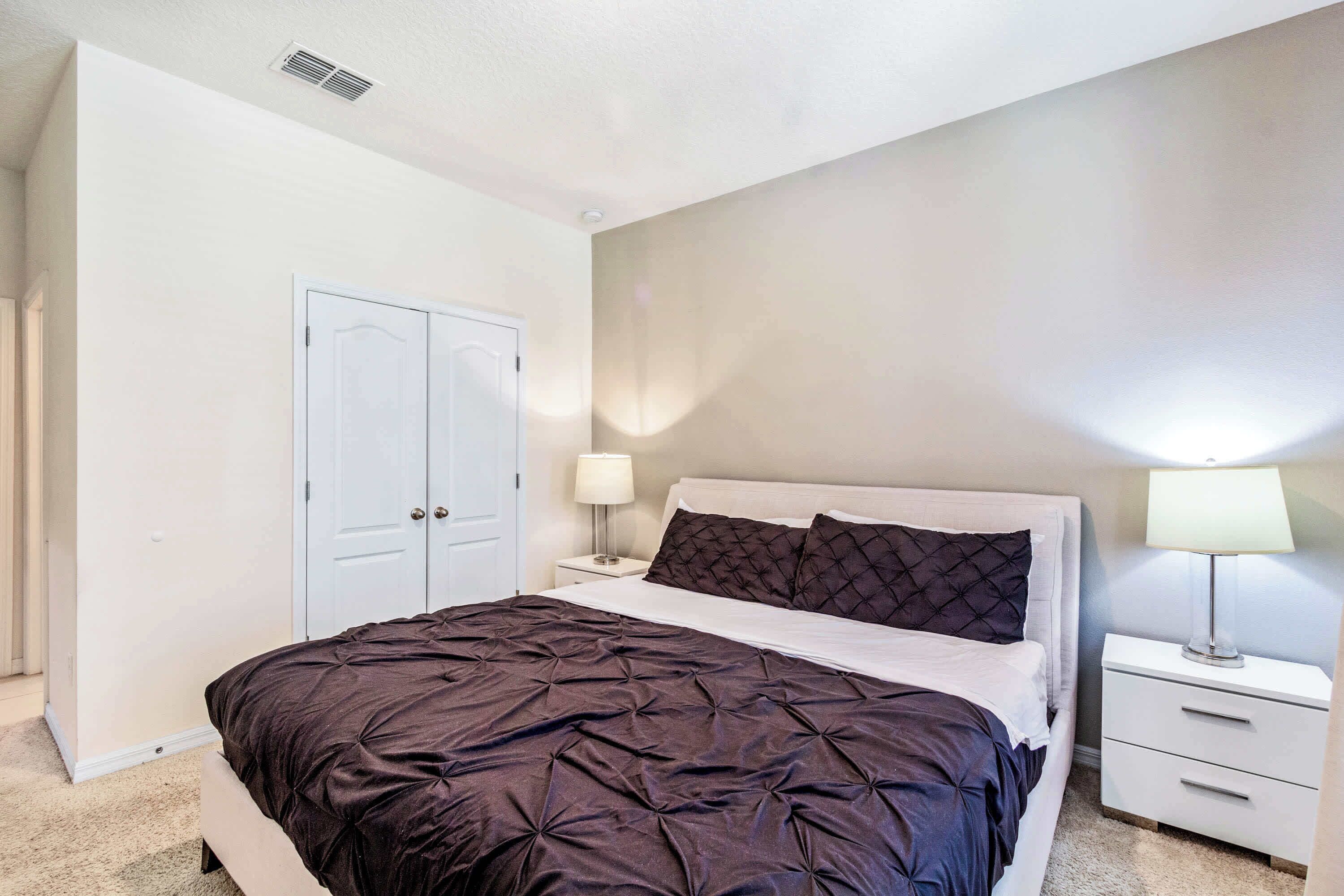 Une chambre à coucher comprenant un lit, deux tables de chevet, une armoire et un luminaire fixé au mur.