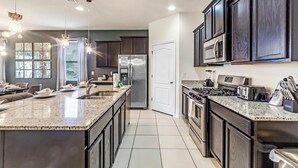 A modern kitchen with dark cabinetry, stainless steel appliances, and a large island.