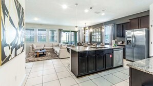 A modern kitchen with a central island, dark cabinetry, and stainless steel appliances.