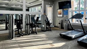 Une salle de sport équipée de machines de cardio, d’appareils de musculation et d’un tapis de course.