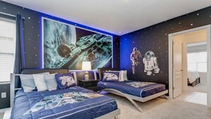 A bedroom with two beds, star-themed decor, and a large space-themed mural.