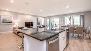 A modern kitchen with a central island, built-in appliances, and a dining area with a large window.