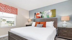 Een slaapkamer met een groot bed, twee nachtkastjes, een raam met zonwering en een schilderij aan de wand.