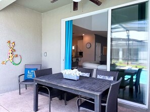 An outdoor patio with a dining table and chairs, a blue cushion, and a decorative wall piece.