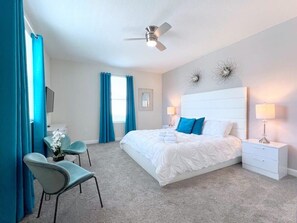 A bedroom with a bed, bedside tables, a desk, and chairs.