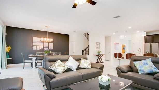 A modern living room with a sofa, coffee table, and a dining area in the background. - Game Room | No Rear Neighbors | 4 Miles Disney 2709 (Kissimmee)