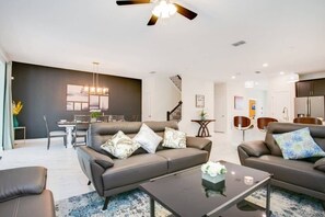 Ein modernes Wohnzimmer mit einer Couch, einem Couchtisch und einem Essbereich im Hintergrund.