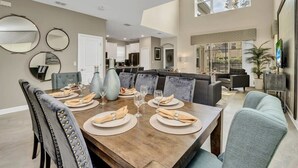 A dining area with a wooden table set for six, surrounded by upholstered chairs. - Splash Pool | Air Hockey | Lazy River | Disney 2755 (Kissimmee)