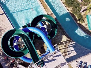 En vattenpark med en stor pool, två vattenrutschbanor och ett område med solstolar.