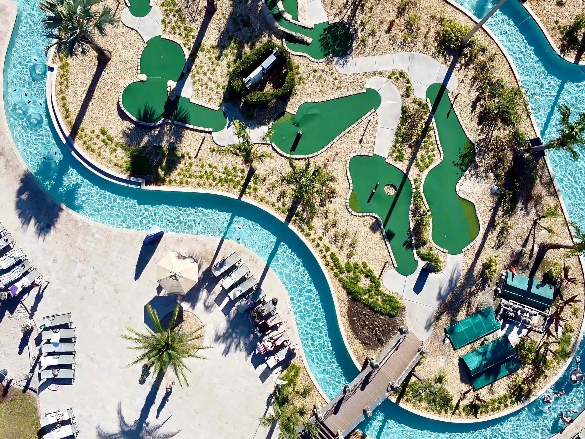 An aerial view of a resort with multiple swimming pools, sun loungers, and palm trees.