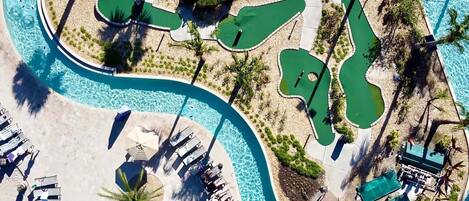 Vue aérienne d’un complexe hôtelier doté de plusieurs piscines, de chaises longues et de palmiers.