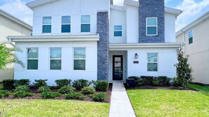 A modern two-story house with a stone accent wall, a front porch, and a well-maintained lawn. - Star Wars | Avengers | Pool | Resort | Disney 4544 (Kissimmee)