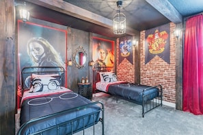 Una habitación con dos camas de metal, una pared de ladrillo y un estandarte de Gryffindor.