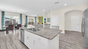 Una cocina moderna con encimeras de granito, armarios blancos y una isla central.