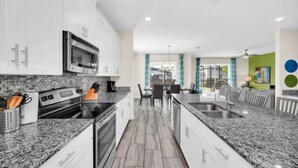 Una cocina moderna con encimeras de granito, electrodomésticos de acero inoxidable y armarios blancos.