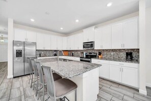 A modern kitchen with white cabinets, stainless steel appliances, and a granite countertop.