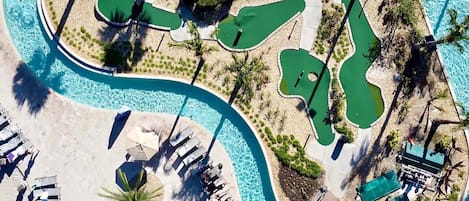 Vista aérea de un complejo turístico con múltiples piscinas, tumbonas y palmeras.