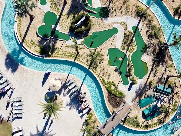 Vista aérea de un resort con múltiples piscinas, tumbonas y palmeras.