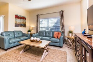 Relax in this inviting living space with a comfortable sofa, wooden coffee table, and large window offering a view of the outdoors.
