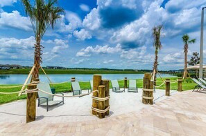 Relax in a serene outdoor seating area overlooking a tranquil body of water, surrounded by palm trees and comfortable lounge chairs.