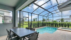 Un'area esterna coperta con piscina, tavolo e sedie, e vista sul paesaggio circostante.