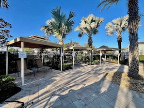A covered outdoor seating area with palm trees, a paved walkway, and a sign indicating 'CABANA 1'.
