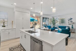 A modern kitchen with a central island, white cabinetry, and pendant lighting.
