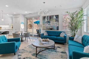 A modern living room with a sofa, chairs, a coffee table, and a large abstract painting.