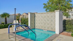 A swimming pool with a tiled wall, a metal ladder, and a clear blue pool. - Desert Serenity | Pool, Spa, BBQ, Near Courses (La Quinta)