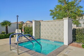 A swimming pool with a tiled wall, a metal ladder, and a clear blue pool. - Desert Serenity | Pool, Spa, BBQ, Near Courses (La Quinta)