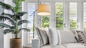 A living room with a white sofa, striped pillows, a woven plant pot, and a floor lamp. - Casa Salinas | Spacious Waterfront Home with Pool (Cabo Rojo)