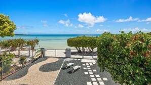 A beachside patio with lounge chairs, a pebble path, and a view of the ocean. - Casa Salinas | Spacious Waterfront Home with Pool (Cabo Rojo)