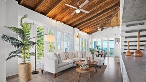 A spacious living area with a high ceiling, a white sofa, a coffee table, and a large potted plant. - Casa Salinas | Spacious Waterfront Home with Pool (Cabo Rojo)