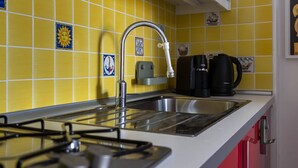 A kitchen with yellow tiles, a stainless steel sink, a gas stove, and a coffee maker. - Siena: appartamento panoramico con terrazza, wi-fi e aria condizionata (Siena)