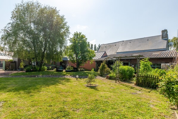 A residential property with a well-maintained lawn, a small garden area, and a wooden fence.