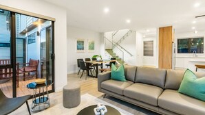 Ein modernes Wohnzimmer mit einer Couch, einem Couchtisch und einem Essbereich mit Stühlen und einem Tisch.
