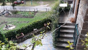 Un quartier résidentiel avec un jardin, une voiture rouge garée dans la rue et un escalier menant à un immeuble.