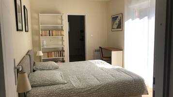 A bedroom with a bed, a bookshelf, a desk, and a chair.
